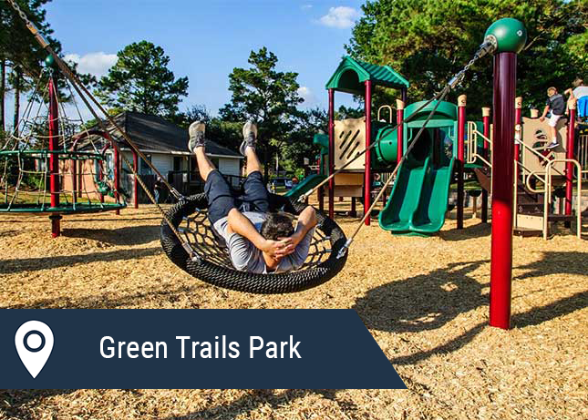Child relaxing in a spinning play module installed by Kraftsman at Green Trails Park in Katy, TX